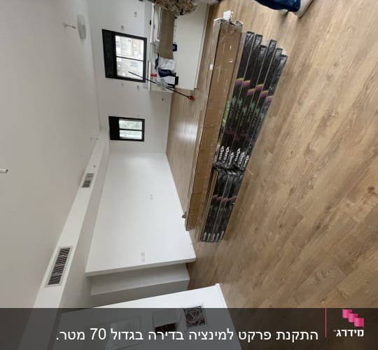חבילות פרקט מונחות על רצפת עץ בחדר ריק